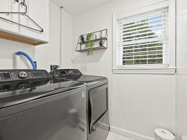 clothes washing area with cabinet space, baseboards, and washer and clothes dryer