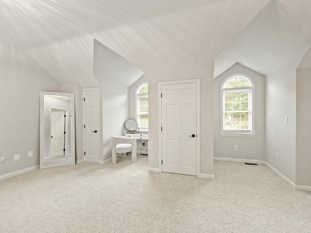 unfurnished bedroom featuring carpet flooring, visible vents, baseboards, and lofted ceiling