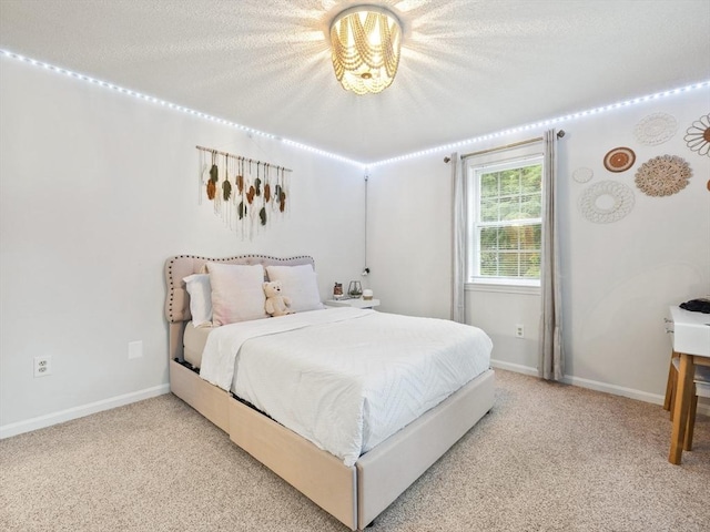 bedroom featuring baseboards, light colored carpet, and a textured ceiling