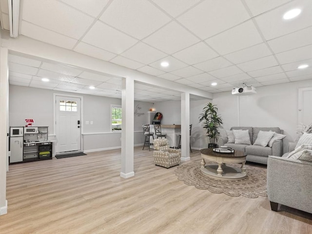 living area with recessed lighting, a paneled ceiling, light wood-type flooring, and baseboards