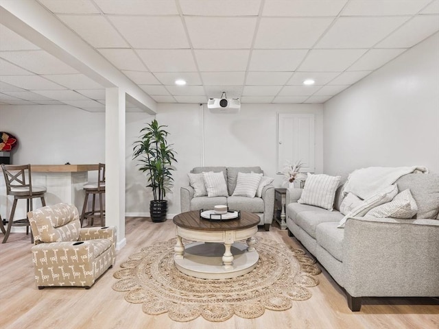 living room featuring a drop ceiling, recessed lighting, baseboards, and wood finished floors