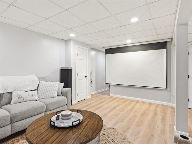 home theater room featuring a paneled ceiling, baseboards, and wood finished floors