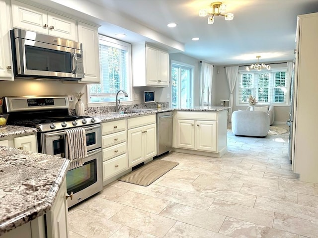 kitchen with a sink, a wealth of natural light, appliances with stainless steel finishes, and a peninsula