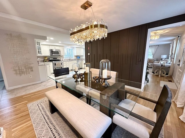 dining room with a notable chandelier, baseboards, and light wood-style floors