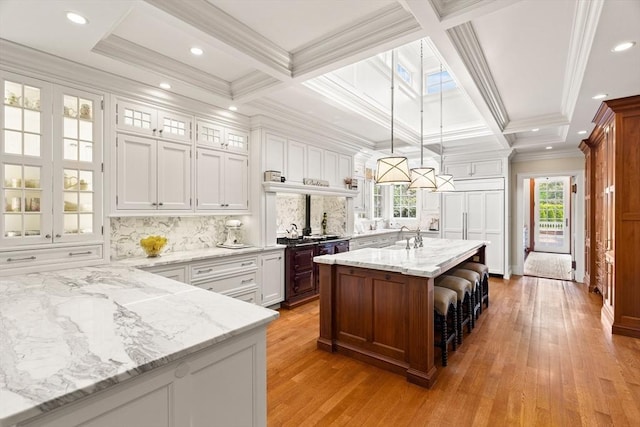 4 Cobb Ave, Manchester, MA 01944 - kitchen featuring light wood finished floors, coffered ceiling, glass insert cabinets, tasteful backsplash, and white cabinetry