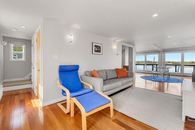 living area featuring light wood-type flooring, baseboards, recessed lighting, and a water view
