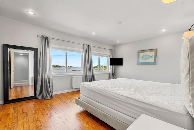 bedroom with baseboards, light wood-style flooring, recessed lighting, and radiator heating unit