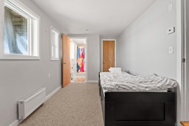 bedroom with radiator heating unit, carpet, multiple windows, and baseboards