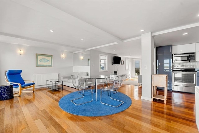 dining room featuring radiator heating unit, wood finished floors, recessed lighting, and baseboards