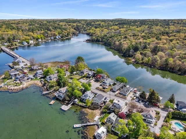 aerial view of property and surrounding area featuring a heavily wooded area, a large body of water, and nearby suburban area