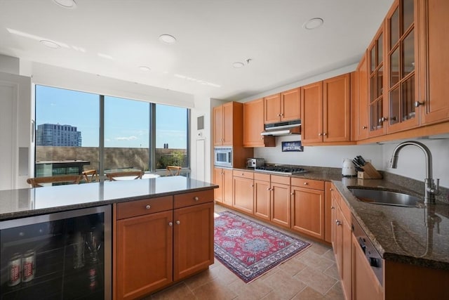 kitchen featuring appliances with stainless steel finishes, wine cooler, dark stone counters, and sink