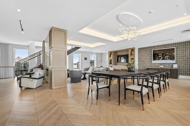 dining area featuring an inviting chandelier, a tray ceiling, and light parquet floors