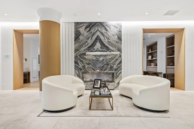 sitting room featuring decorative columns, built in shelves, light tile patterned floors, and a high end fireplace