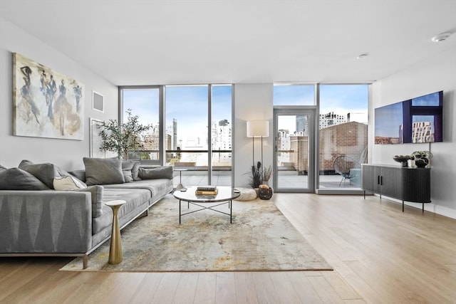 living room featuring a wealth of natural light, light hardwood / wood-style floors, and floor to ceiling windows