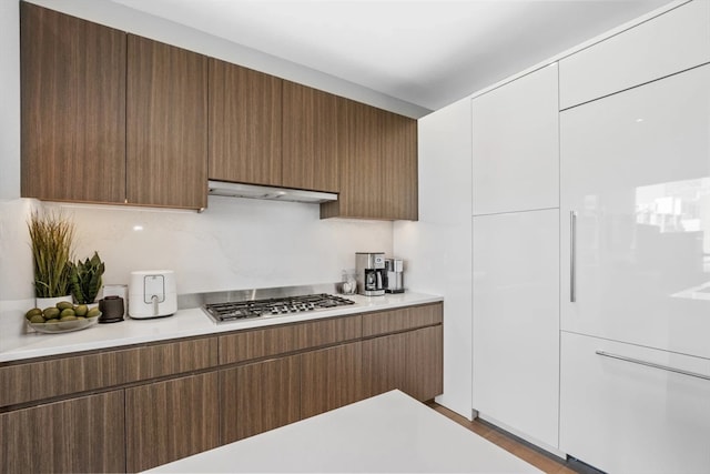 kitchen with range hood, white cabinets, and stainless steel gas cooktop