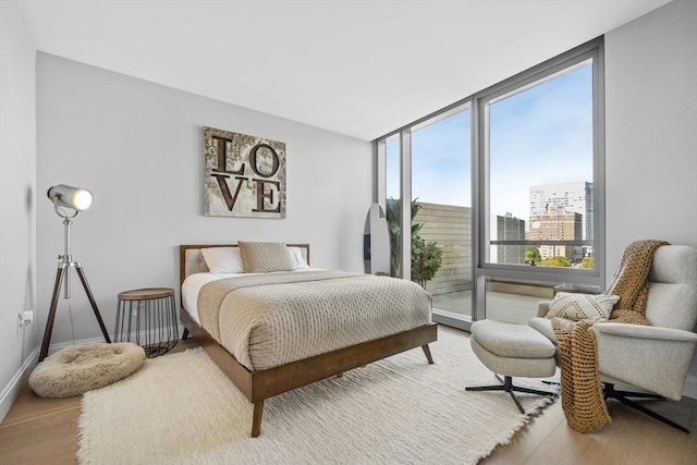 bedroom featuring a wall of windows and light hardwood / wood-style floors