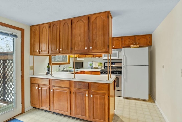 kitchen featuring white appliances, kitchen peninsula, and sink