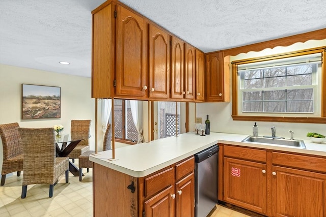 kitchen featuring stainless steel dishwasher, kitchen peninsula, sink, and a textured ceiling