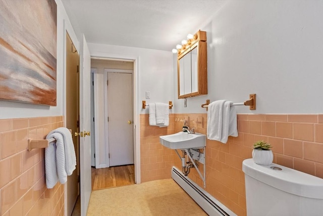 bathroom featuring tile walls, sink, toilet, and baseboard heating