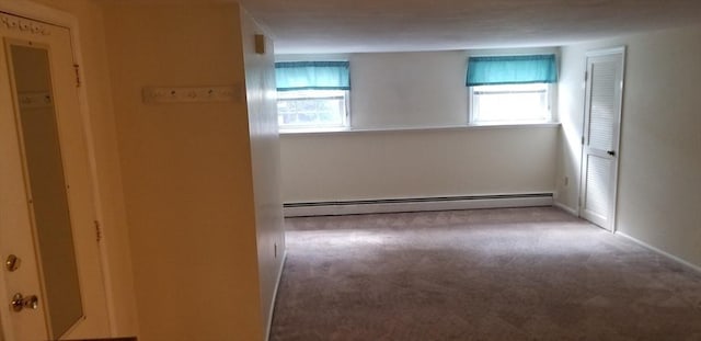 carpeted spare room featuring a baseboard heating unit