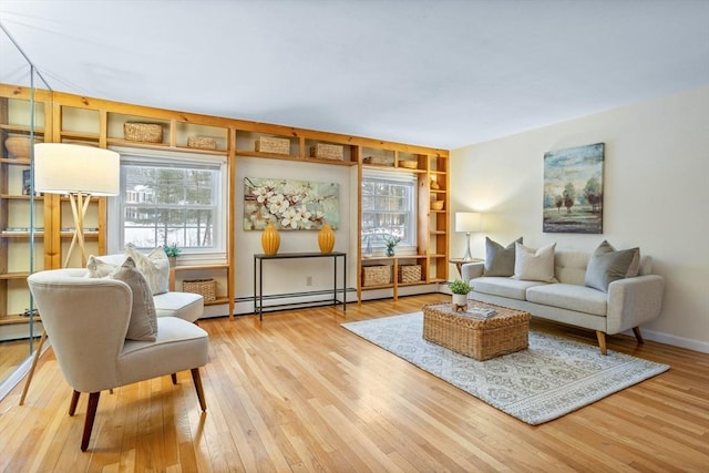 living area with a baseboard heating unit and light hardwood / wood-style floors