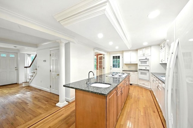 1095 Main St, Hanover, MA 02339 - kitchen with white appliances, a kitchen island with sink, light wood-style floors, dark stone counters, and ornamental molding