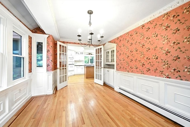 1095 Main St, Hanover, MA 02339 - unfurnished dining area featuring a baseboard heating unit, wallpapered walls, a chandelier, a wainscoted wall, and light wood finished floors