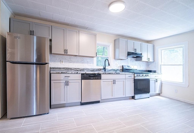 73 Sladen St, Dracut, MA 01826 - kitchen featuring appliances with stainless steel finishes, extractor fan, backsplash, gray cabinetry, and light stone countertops