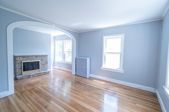 73 Sladen St, Dracut, MA 01826 - unfurnished living room featuring radiator, wood finished floors, a fireplace, crown molding, and arched walkways