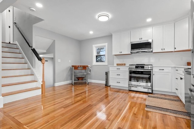 kitchen featuring stainless steel appliances, white cabinetry, and light hardwood / wood-style floors