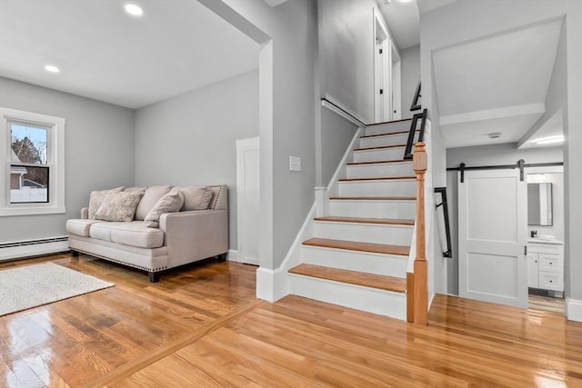 staircase featuring hardwood / wood-style flooring, a barn door, and a baseboard radiator