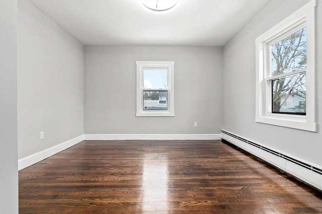 empty room with baseboard heating and dark hardwood / wood-style floors