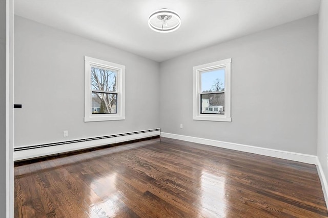 spare room featuring dark hardwood / wood-style floors, a healthy amount of sunlight, and baseboard heating