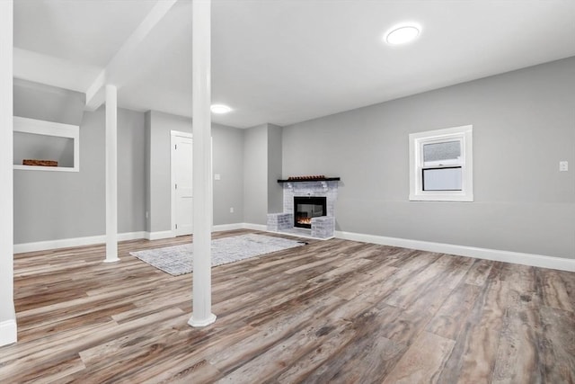 basement featuring a brick fireplace and light hardwood / wood-style floors