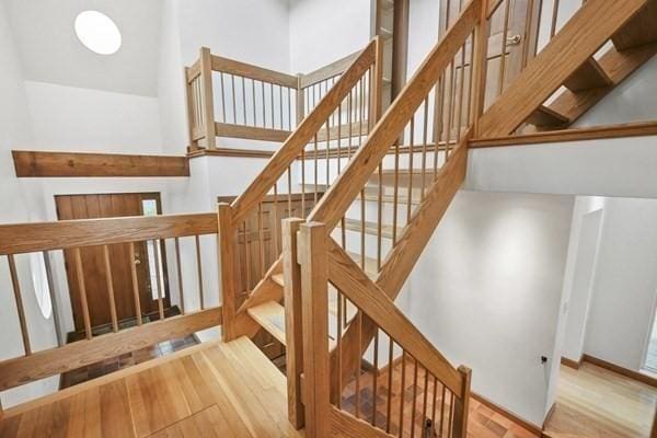 stairway featuring a towering ceiling and wood finished floors