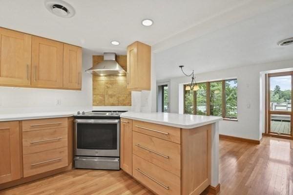 kitchen featuring visible vents, a peninsula, stainless steel electric range oven, wall chimney range hood, and light brown cabinetry