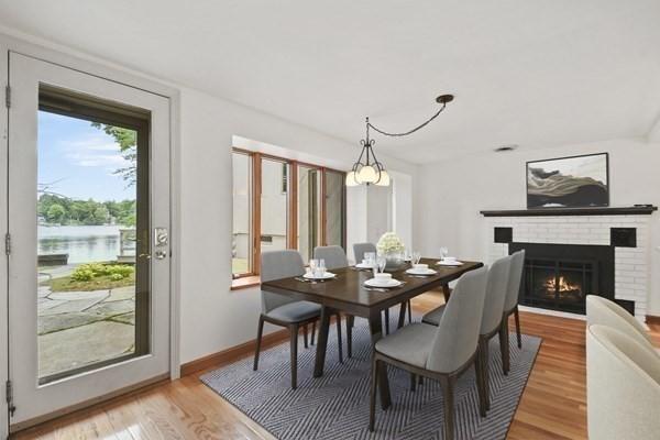 dining room featuring baseboards, a brick fireplace, and light wood finished floors