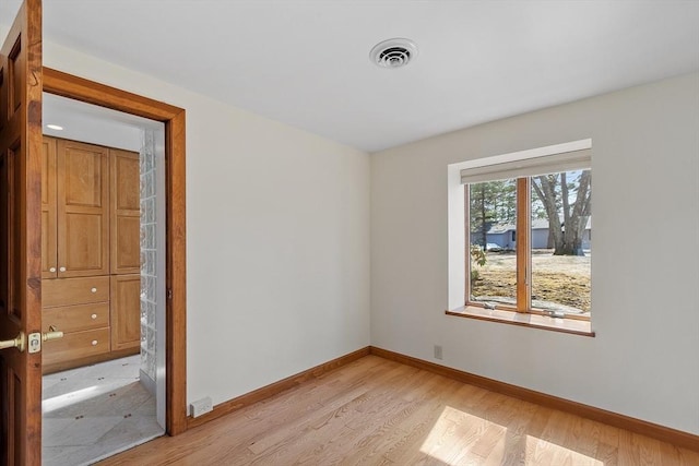 spare room with baseboards, visible vents, and light wood-style floors