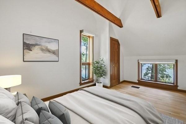 bedroom featuring lofted ceiling with beams, visible vents, multiple windows, and wood finished floors