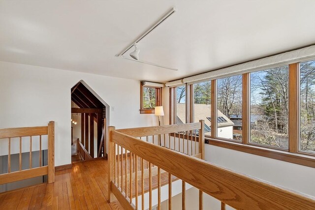 hallway featuring rail lighting, an upstairs landing, and hardwood / wood-style flooring