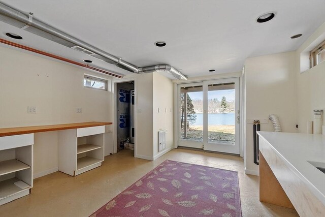 interior space with finished concrete flooring, a water view, and baseboards