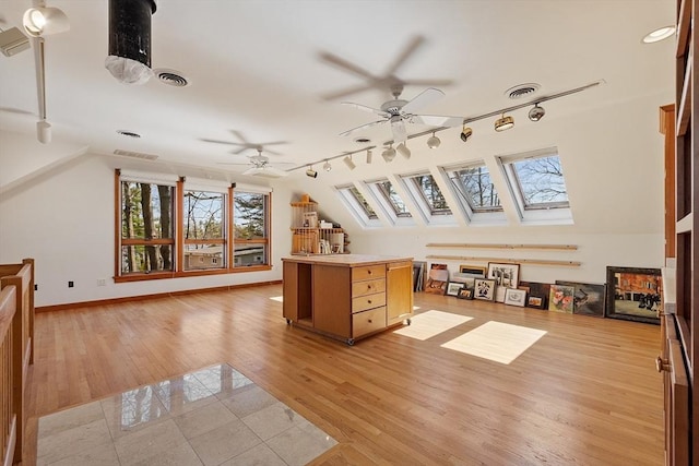 additional living space with ceiling fan, visible vents, lofted ceiling with skylight, and light wood-type flooring