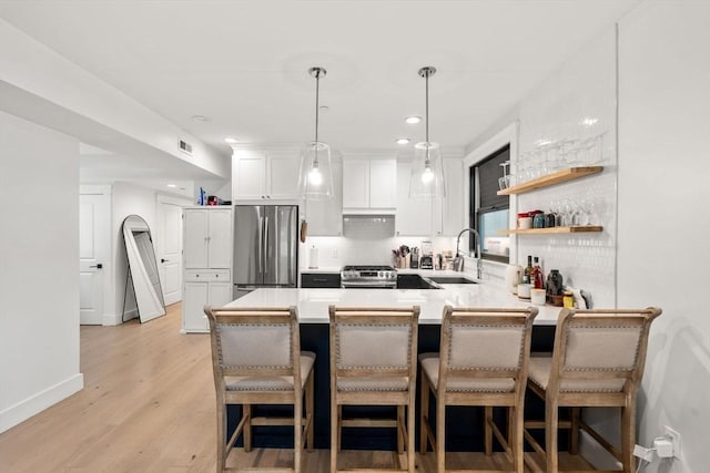 331 Chelsea St Unit 1, Boston, MA 02128 - kitchen featuring stainless steel appliances, a sink, a peninsula, decorative backsplash, and white cabinetry