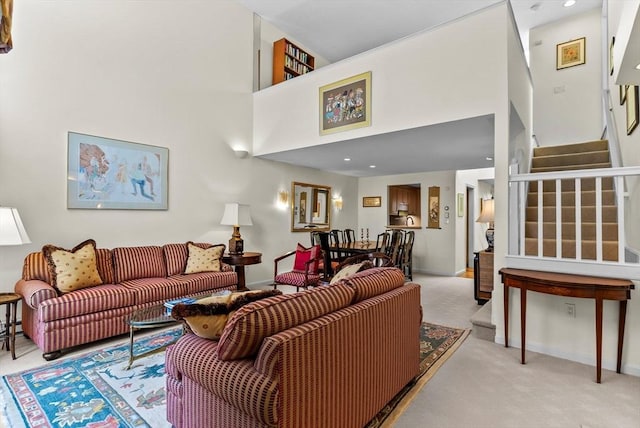 living area featuring baseboards, stairway, a towering ceiling, and light colored carpet