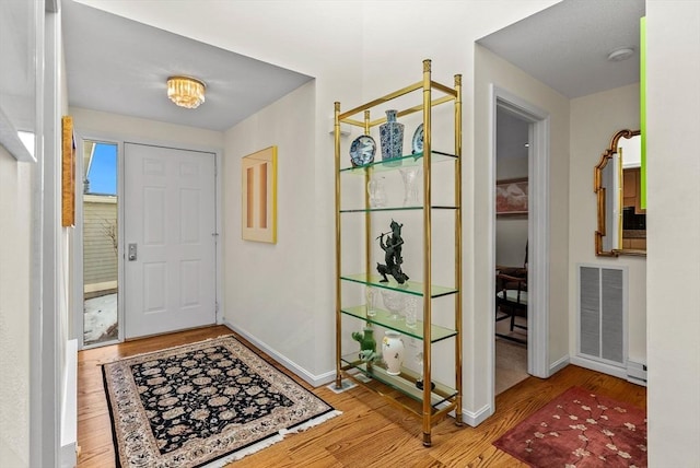 entryway featuring baseboards, visible vents, and wood finished floors