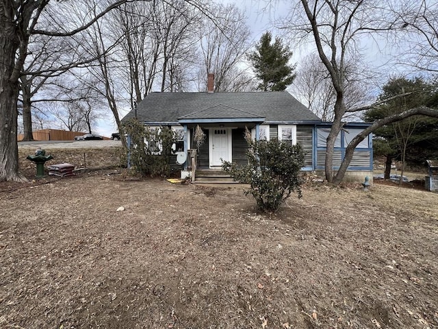 bungalow featuring a chimney and roof with shingles