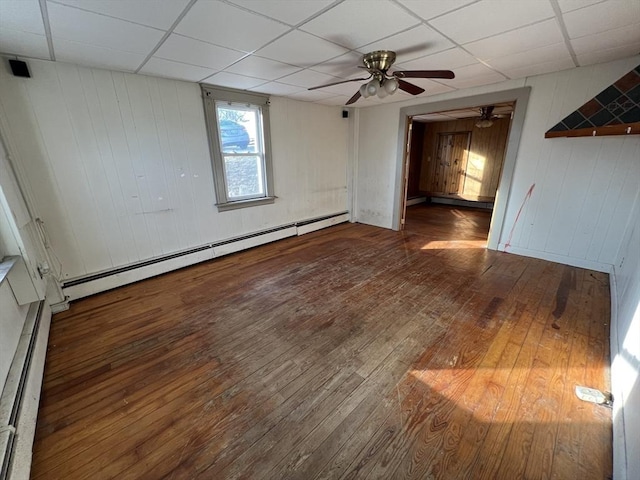 empty room featuring a baseboard radiator, a drop ceiling, and hardwood / wood-style floors