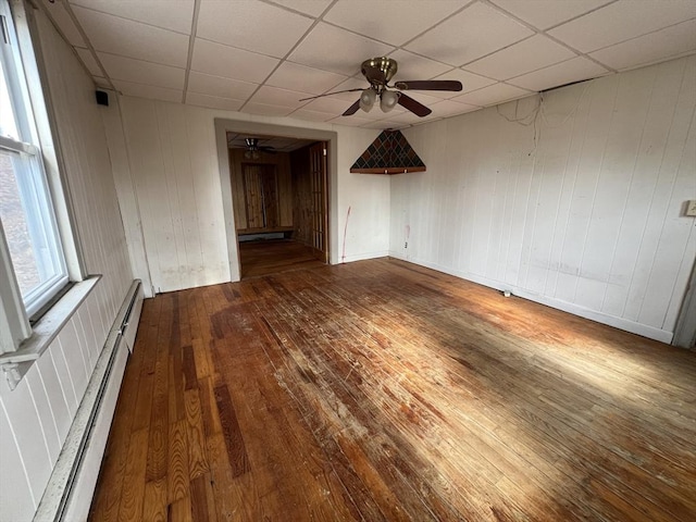 spare room featuring a paneled ceiling, hardwood / wood-style flooring, ceiling fan, and baseboard heating