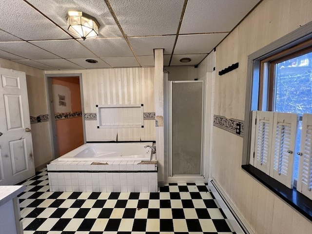 full bath featuring tile patterned floors, wood walls, a shower stall, a baseboard heating unit, and a bath