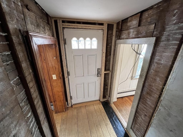 doorway to outside with a baseboard heating unit, wooden walls, and hardwood / wood-style floors